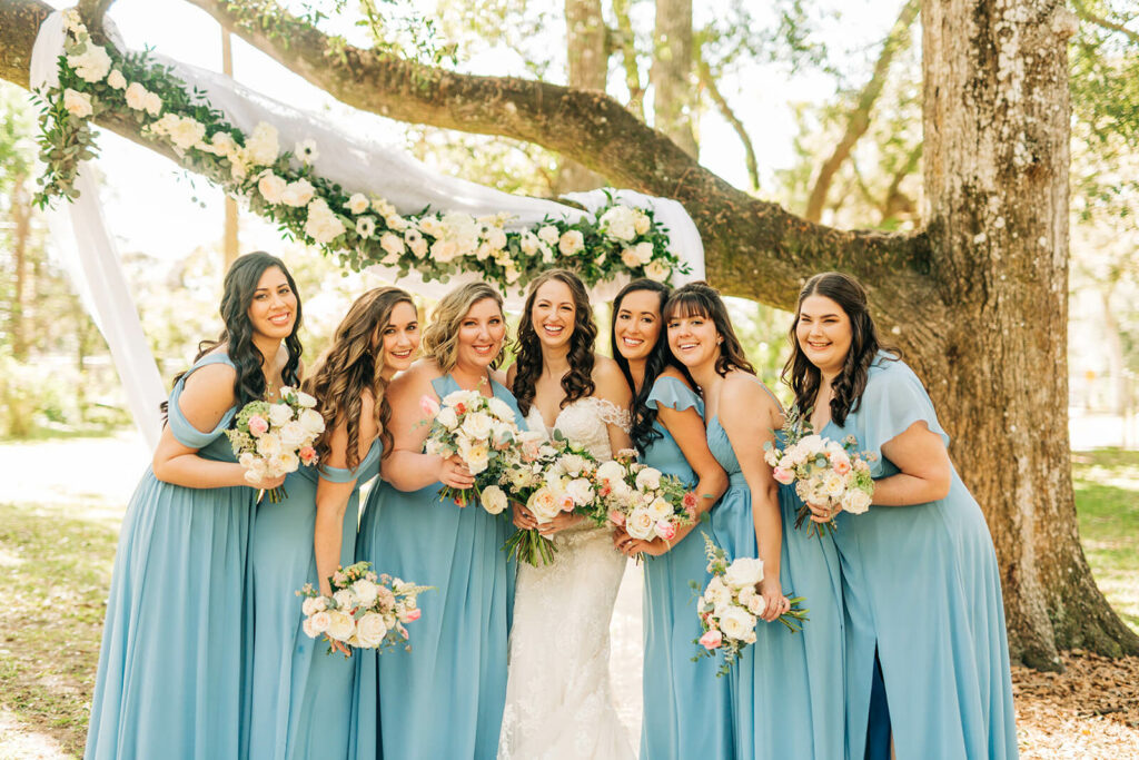 Bridal Party In Blue Holding Floral Bouquets