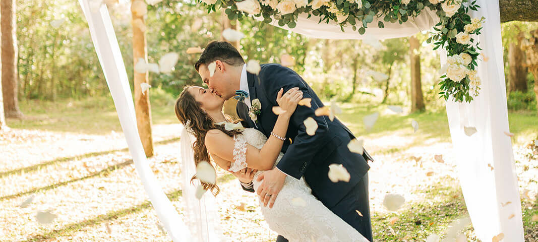 Bride And Groom Kiss Under Floral Arch