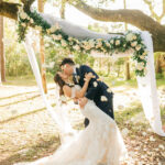 Bride And Groom Kiss Under Floral Arch